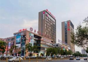 dos edificios altos con coches en una calle de la ciudad en Echarm Hotel Aegean Shopping Park Zhonghuan Plaza, en Tangshan