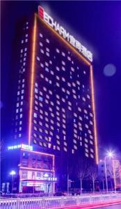 a tall building with a sign on it at night at Echarm Hotel Zibo Zhangdian District Government Polytechnic University Store in Zibo