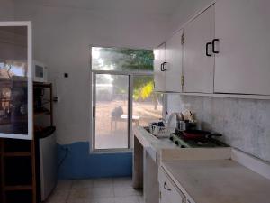 a kitchen with white cabinets and a sink and a window at Luz del Mar Paredón in Sipacate