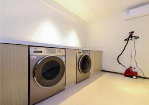 a laundry room with two washing machines and a red vacuum at Echarm Hotel Wuhan Huangpu Erqi Xiaolu Metro Station in Jiang'an