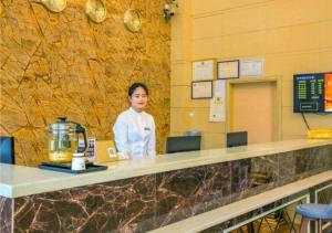 a woman is standing behind a counter in a restaurant at Jtour Inn Fengcheng Railway Station Jianyi Avenue Xincheng in Fengcheng