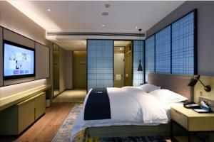 a bedroom with a large bed and a flat screen tv at Echarm Hotel Huaihua Vocational College in Huaihua