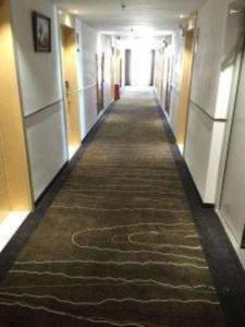 a long hallway with a long carpet in a building at City Comfort Inn Yi'Ning Jichang Road Shanghaicheng in Kipekyüzi
