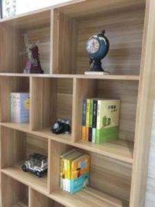 a wooden book shelf with books and a clock at City Comfort Inn Yi'Ning Jichang Road Shanghaicheng in Kipekyüzi