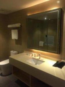 a bathroom with a sink and a toilet and a mirror at City Comfort Inn Yi'Ning Jichang Road Shanghaicheng in Kipekyüzi