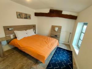 a bedroom with a bed with an orange blanket at L'escale de Compostelle, centre ville à 5 minutes du Canal in Moissac