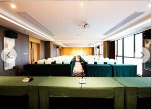einen Konferenzraum mit grünen Tischen und weißen Stühlen in der Unterkunft Echeng Hotel Sanming City Government RT-Mart in Sanming
