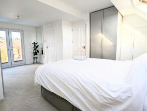 Un dormitorio blanco con una cama grande y una ventana en Beautiful 4 Bed Portsmouth Home Bright & Modern with Garden & Free Parking & Spa Bath & Fully Equiped Kitchen Perfect For Work or The Family en Portsmouth