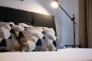 1 cama con almohadas blancas y negras y lámpara en Central View Apartment 1, en Blagoevgrad