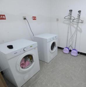 a laundry room with a washing machine and a washer at Echeng Hotel Beihai Hunan Road Old Street in Gaode