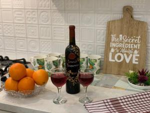 a bottle of wine and a bowl of oranges and wine glasses at Сozy three-room apartment with 2 separate bedrooms in the center of Tbilisi in Tbilisi City