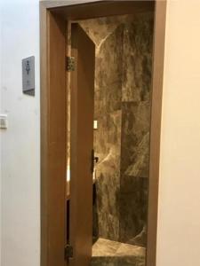 a door to a bathroom with a stone wall at Borrman Hotel Liuzhou Guizhong Avenue Liugao in Liuzhou