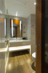 La salle de bains est pourvue d'un lavabo, de toilettes et d'un miroir. dans l'établissement Borrman Hotel Jingzhou Jiangjin West Road Wanda Plaza Fantawild, à Caoshi