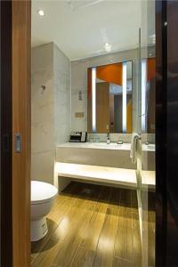 La salle de bains est pourvue de toilettes, d'un lavabo et d'un miroir. dans l'établissement Borrman Hotel Jingzhou Jiangjin West Road Wanda Plaza Fantawild, à Caoshi