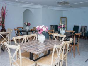 Elam Guest House في امتاتا: طاولة خشبية مع كراسي و مزهريات عليها زهور