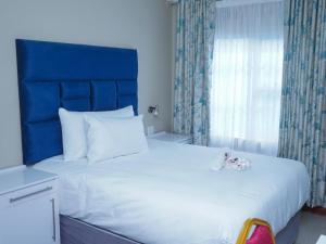a bedroom with a large white bed with a blue headboard at Elam Guest House in Mthatha