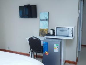 Cette chambre comprend un lit, un four micro-ondes et un réfrigérateur. dans l'établissement Elam Guest House, à Mthatha