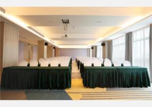 una sala de conferencias con mesas verdes y sillas blancas en Echarm Hotel Liuzhou Liunan Wanda Plaza en Liuzhou