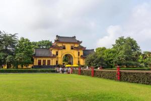 um edifício amarelo com uma cerca em frente a um parque em Echarm Hotel Guilin High-tech Wanda Li Lake em Guilin