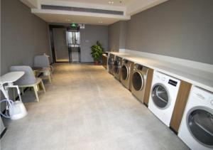 a laundry room with a row of washing machines at Echarm Hotel Beihai Yintan in Dianbailiao