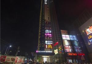Echarm Hotel Beihai Yintan في Dianbailiao: مبنى طويل مع علامات نيون في مدينة في الليل