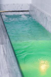 een zwembad van groen water naast een muur bij The Secret Garden Pool Villa Phuket in Ban Na Bon