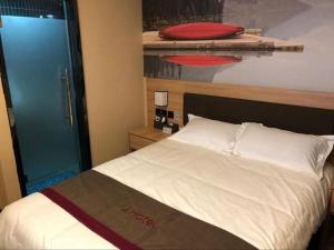 1 dormitorio con cama blanca y puerta azul en Thank Inn Hotel Anhui Chuzhou Fengyang County Bus Station en Shanhoujie