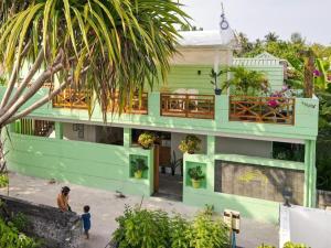 a green house with a balcony with people standing in front of it at Turtle Maldives in Omadhoo