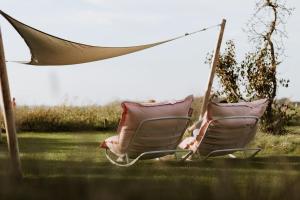 two chairs sitting in a hammock in a yard at HEI15 in Sint Geertruid
