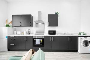 een keuken met zwarte kasten en een wasmachine en droger bij New Apartment in Brierley Hill - Parking - Wifi - Netflix - Top Rated - 309O in Birmingham