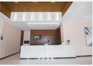 a woman sitting at a reception desk in a building at City Comfort Inn Shantou Daxue Road in Shantou