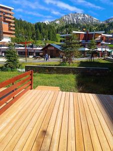 a wooden deck with a bench in a park at Résidence Pelvoux - Studio pour 4 Personnes 844 in Aime-La Plagne