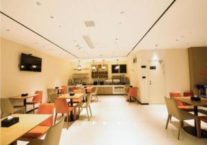 a dining room with tables and chairs and a kitchen at City Comfort Inn Shiyan Walking Street in Shiyan
