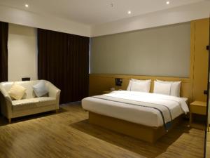 a bedroom with a large bed and a chair at City Comfort Inn Yulin Yufu Road Industrial Products Market in Yulin