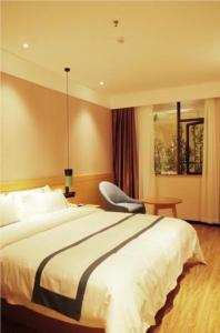 a hotel room with a bed and a chair at City Comfort Inn Jingdezhen Walking Street Yuyaochang in Jingdezhen