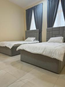 two beds in a bedroom with blue curtains at Star building in Khor Fakkan