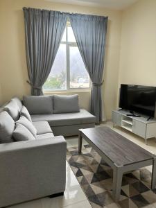 a living room with a couch and a tv at Star building in Khor Fakkan