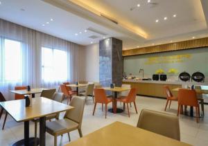 a restaurant with tables and chairs and a kitchen at City Comfort Inn Jingzhou Hongxing Road Food Street in Pu-ho
