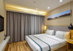 Cette chambre comprend un grand lit et une télévision. dans l'établissement City Comfort Inn Jingzhou Hongxing Road Food Street, à Pu-ho