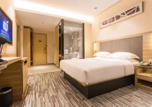 a hotel room with a large bed and a television at City Comfort Inn Wuzhou Arcade City Sanzongfu in Wuzhou