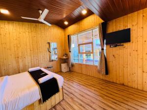 - une chambre avec un lit et un ventilateur de plafond dans l'établissement Arya's Village, à Mahabaleshwar