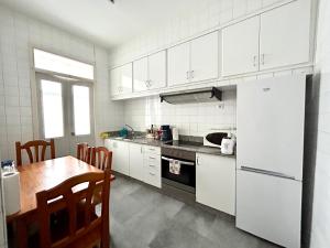 eine Küche mit einem Tisch und einem weißen Kühlschrank in der Unterkunft Vibes Coruña-Tovar 42 in A Coruña