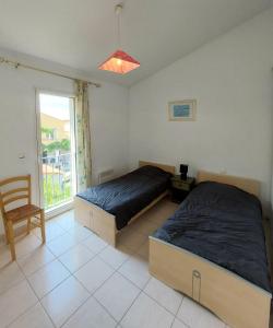 1 dormitorio con 2 camas, silla y ventana en soleil catalan latour bas elne 65m2 2ch ok animaux 4 pers chéques vacances en Latour-Bas-Elne