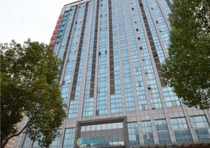 a tall building with glass windows on the side of it at City Comfort Inn Wuhan Guanggu Finance Port in Liufangling