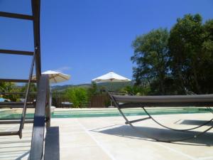 a pool with two chairs and umbrellas next to it at Les Tournillayres in Bédoin
