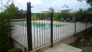 een hek rond een zwembad met een ijzeren hek bij Les Tournillayres in Bédoin