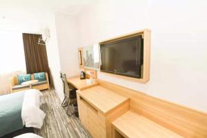 a hotel room with a bed and a desk and a television at City Comfort Inn Zhenjiang Dashikou Suning Plaza in Zhenjiang