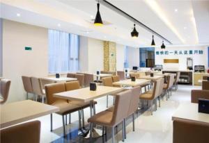 un restaurant avec des tables et des chaises dans une cafétéria dans l'établissement City Comfort Inn Foshan Jihua Creative Park, à Foshan