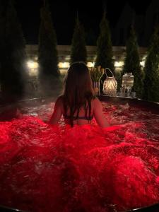 a girl sitting in a tub of red blanket at DOMKI LAURA z sauną i gorącą balią z jacuzzi in Jastrzębia Góra