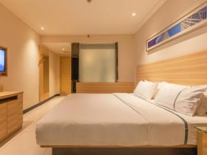1 dormitorio con 1 cama blanca grande y TV en City Comfort Inn Wuhan Zoo Guobo Maying Road Metro Station en Hanyang